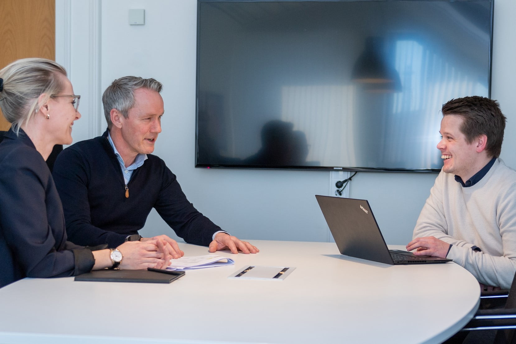 3 rådgivere sitter rundt et bord i dialog