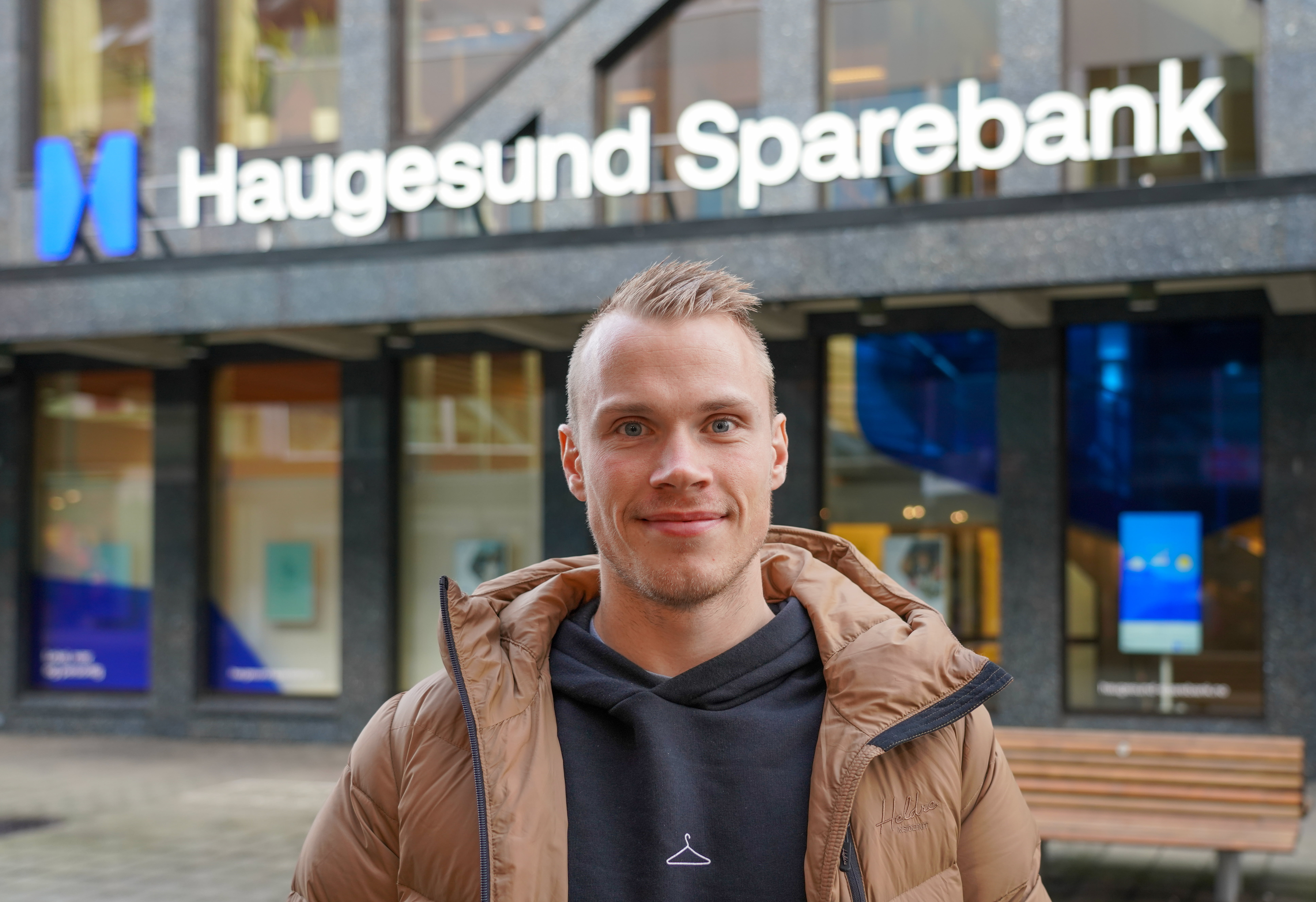Ung mann med kort lyst hår står foran Haugesund Sparebank