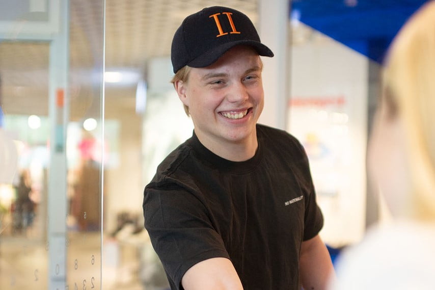 Ung mann i caps hilser på en person utenfor bildet