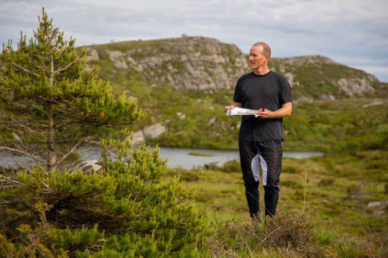 En mann står med et orienteringskart i fjellheimen