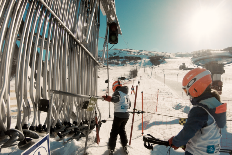 Barn med hjelm på vei opp i skitrekk
