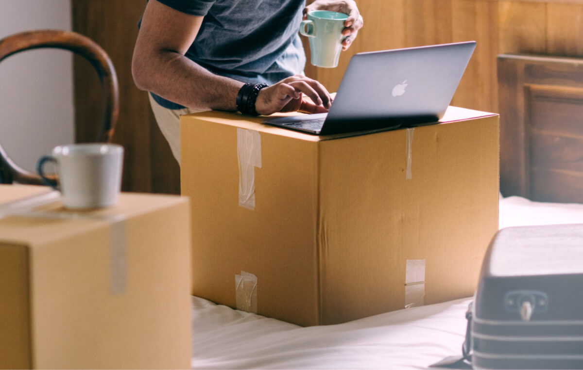 En mann skriver på en laptop som ligger på en flytteeske