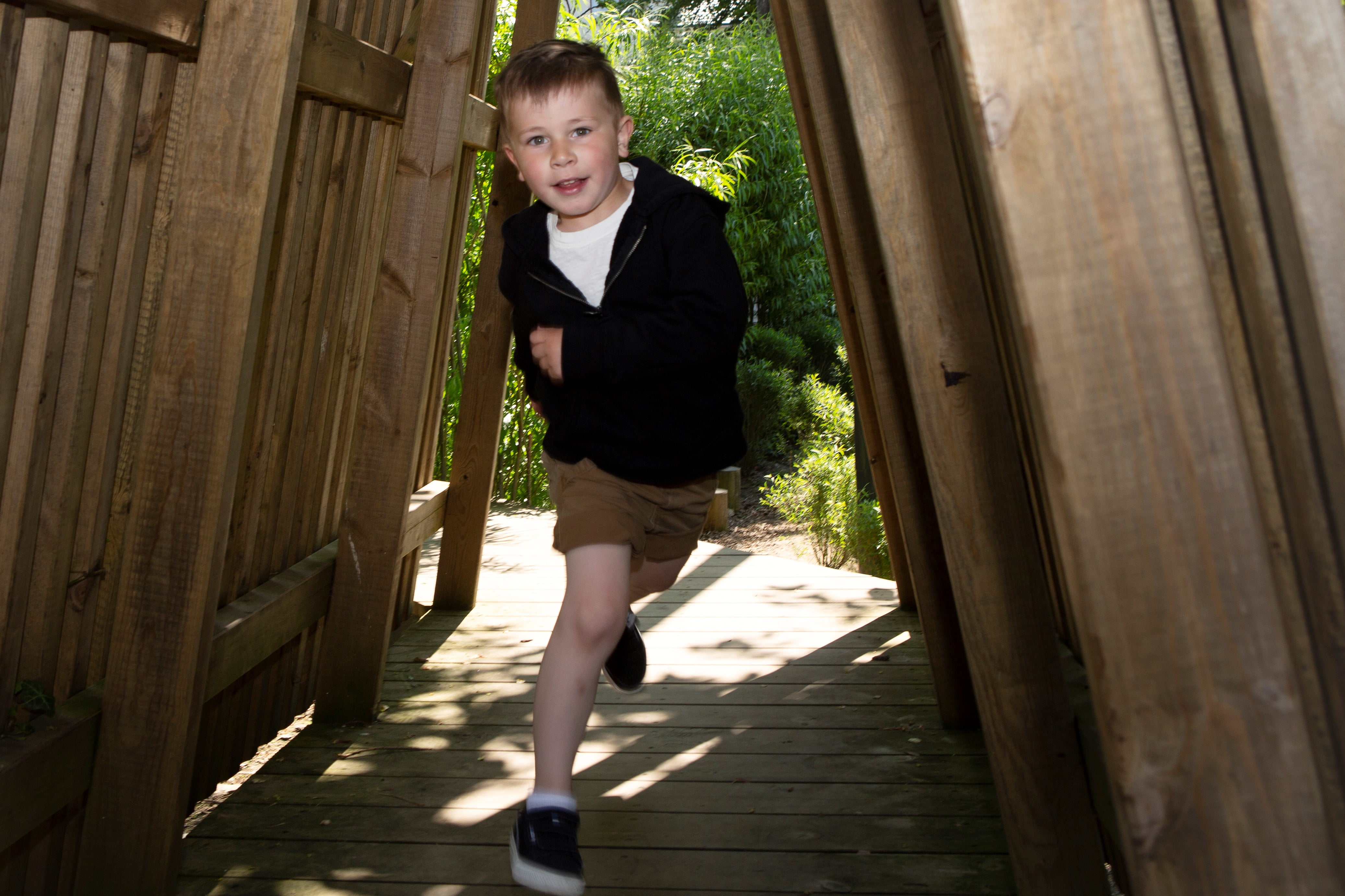 En ung gutt løper under en lekehytte