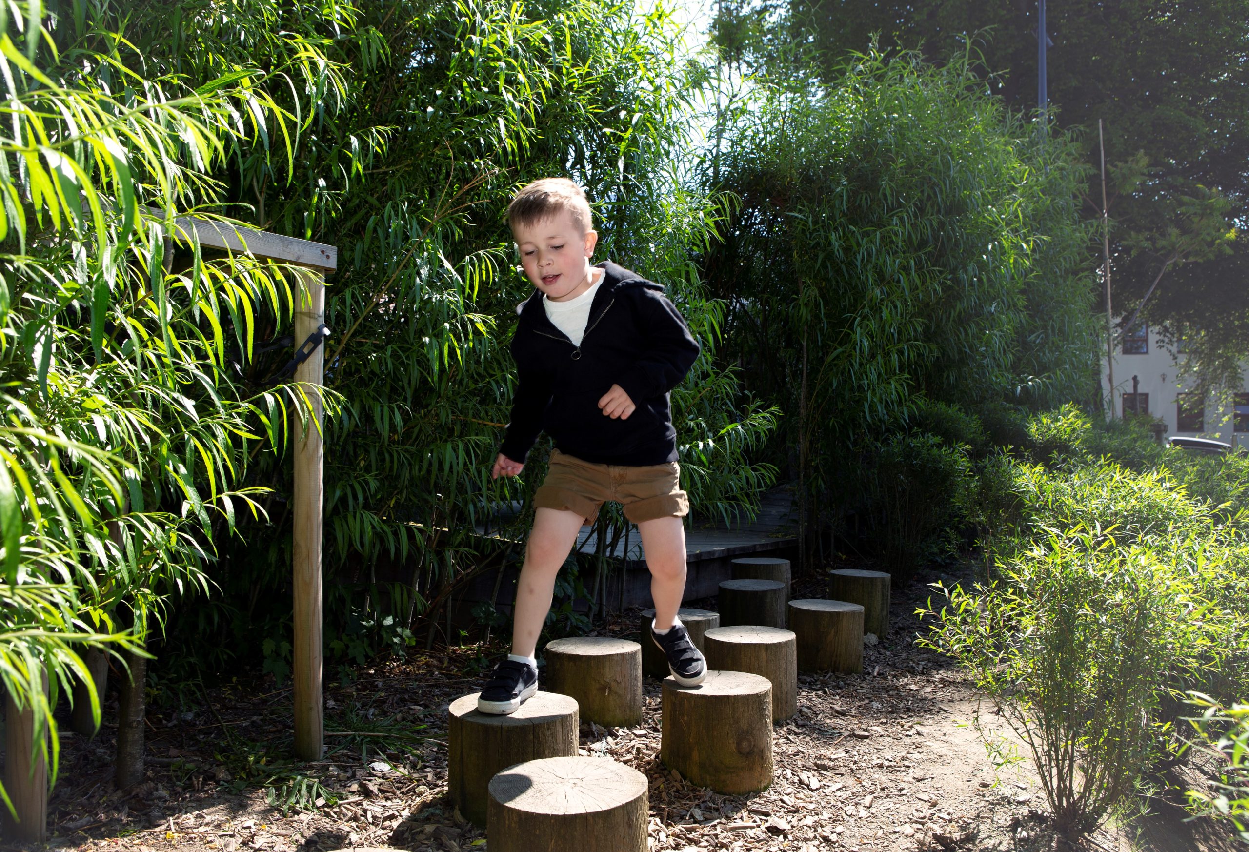 En ung gutt hopper mellom stubber i en park