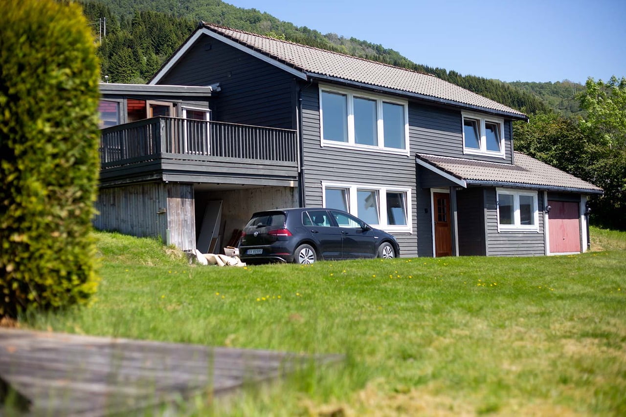 Bilde av et grått hus med en bil foran