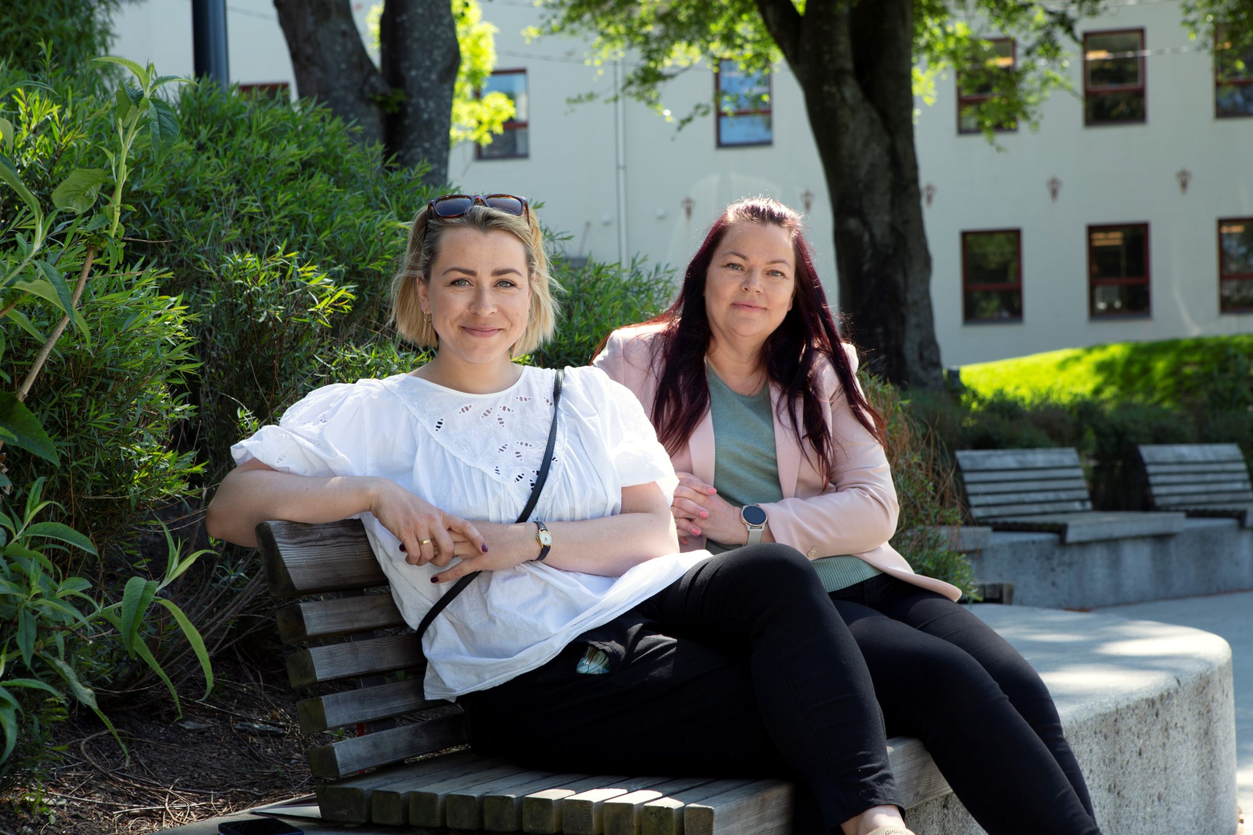 To blide damer sitter på en benk i parken