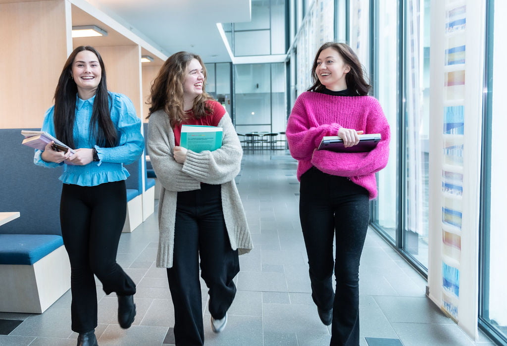 Tre kvinnelige studenter går i gangen på Høgskulen
