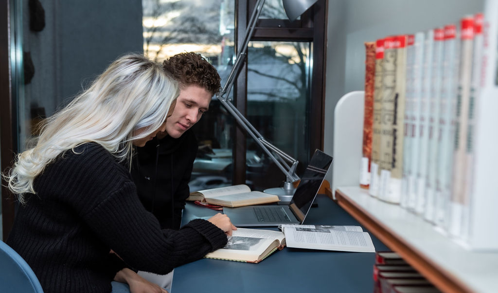 En mannlig og en kvinnelig student studerer sammen på en lesesal